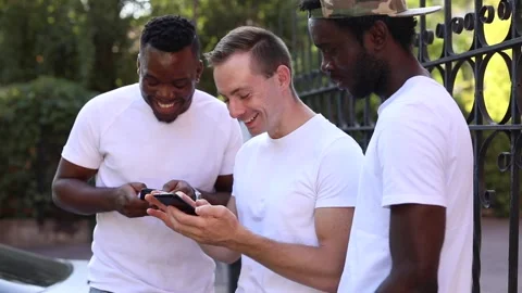 Three multiracial students communicate with each other, look at the phone and Stock Footage 140976512