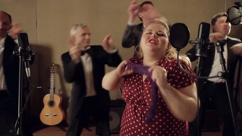 Three musicians and a cheerful fat girl sing and dance in the recording studio. Stock Footage 80664450