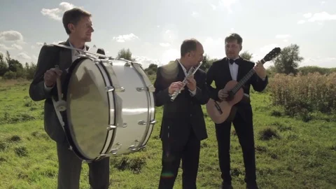 Three musicians play instruments on the field. Stock Footage 80719211
