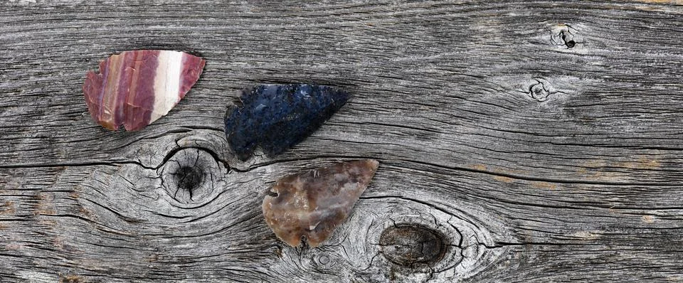Three Native American arrowheads on rustic wood Stock Photos