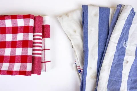 Three new red checkered kitchen picnic towels folded versus old dirty torn blue Stock Photos