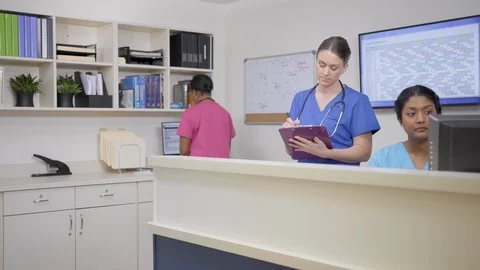 Three nurses working at nursing station, camera moves left then right Stock Footage 109502240