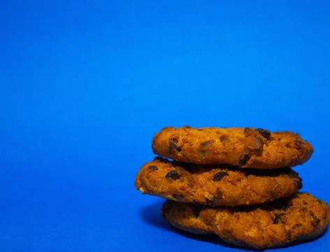 Three oat biscuits with a crumb of chocolate on a blue background Stock Photos