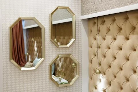 Three octagonal mirrors in gold tones hang on the wall. Decor elements for a  Stock Photos
