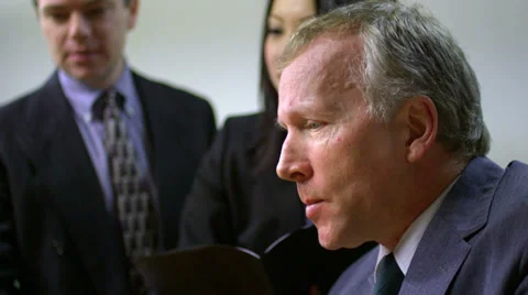 Three office workers work together and the senior member types on a laptop Stock Footage 33831745