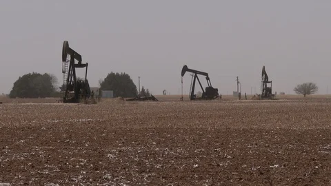 Three oil pump jacks in wind blown Permian Basin local, 4K. Stock Footage