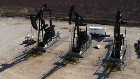 Three Oil Well Pump Jacks and Some Tanks, Brazos County, Texas, USA Stock Footage 145949090