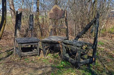 Three old burned and destroyed wooden chairs in the backyard Stock Photos