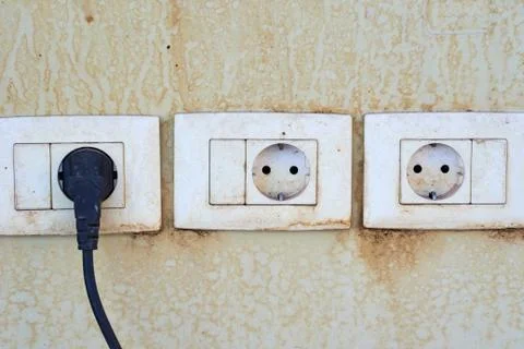 Three old damger sockets on a wall with cord cable plugged in one socket Stock Photos