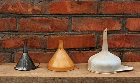 Three old fashioned funnels from metal and plastic on rustic wooden surface Stock Photos