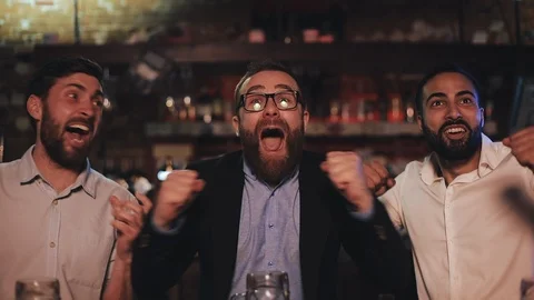 Three old friends drinking beer, cheering together in a pub. Football fans Stock Footage 109257536