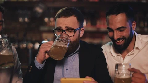 Three old friends watching video on smartphone and drinking draft beer in the Stock Footage 109596505