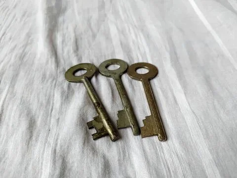 Three old metal keys on light wooden surface Stock Photos