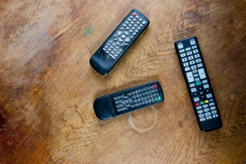 Three old remote controls from televisions and videos on destroyed table surf Stock Photos