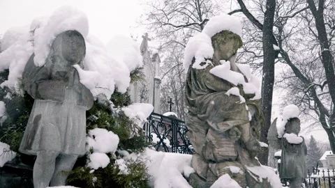 Three old statues of little Angels. XIX century cemetery on snowy winter day. 스톡 동영상 286131790