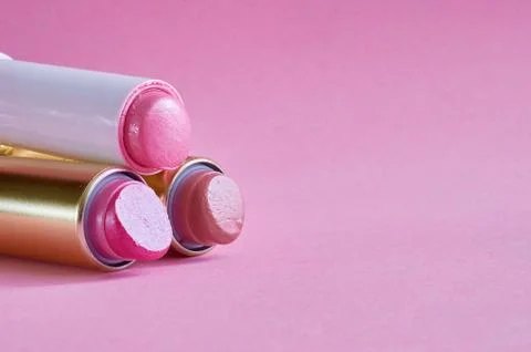 Three old used lipstick tubes lie on a pink background Stock Photos