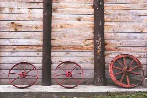 Three old wheels to a cart on the background of a wooden wooden tower wall on a Stock Photos