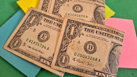 Three one dollar bills resting on bright colorful sticky note pads Stock Photos