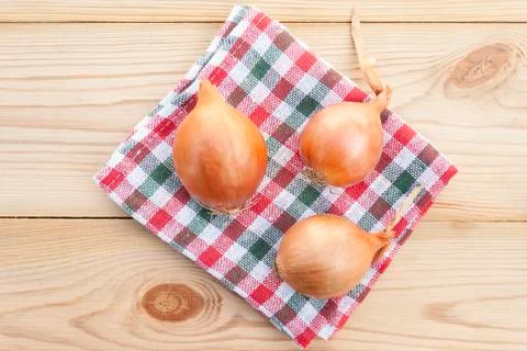 Three onions on a wooden table Stock Photos