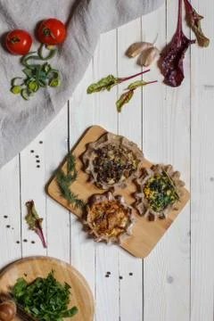 Three open small buckwheat flour pies with vegetarian fillings on white board Stock Photos