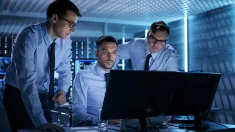 Three Operations Engineers Solving Problem in a Monitoring Room. In System Co Foto stock