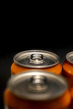 Three orange beverage cans with open tops are arranged in a close-up shot Stock Photos