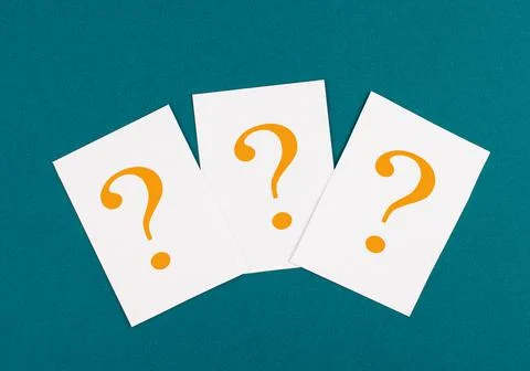 Three orange colored question marks on paper, petrol background, looking for an Stock Photos