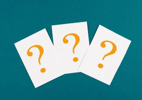 Three orange colored question marks on paper, petrol background, looking f... Stock Photos