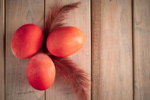 Three orange easter eggs and feathers on a wooden background. Stock Photos