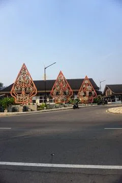 Three orange gunungan puppet statue installations stand along the roadside Stock Photos