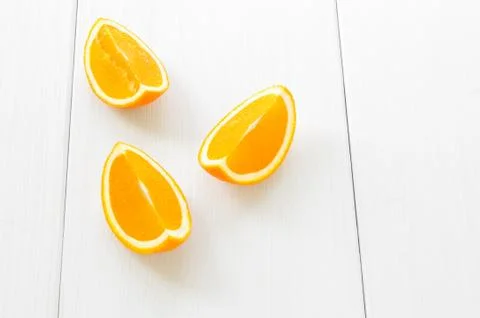 Three orange segments or slices on white wooden surface background. Simple co Stock Photos