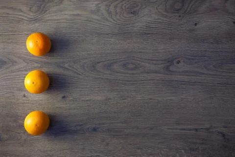 Three oranges are on empty dark wooden table Stock Photos