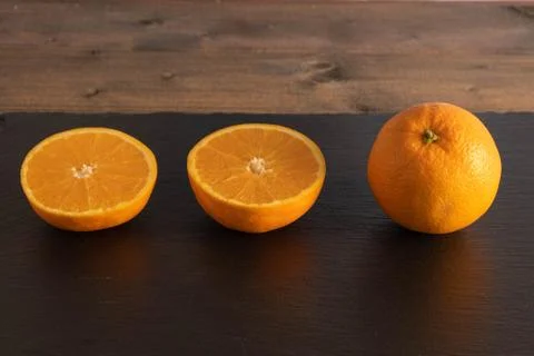 Three oranges on a black stone. Stock Photos
