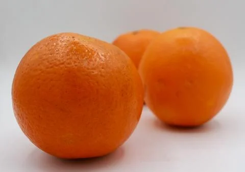 Three oranges grouped closely on a plain white background, highlighting their Stock Photos