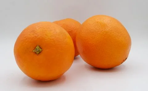 Three oranges grouped closely on a plain white background, highlighting their Stock Photos