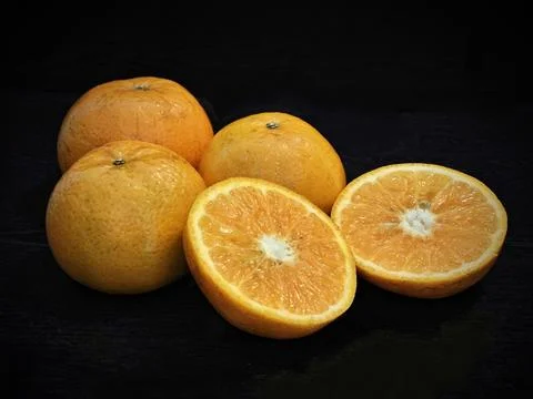 Three oranges, one orange cut open and sitting on top of each other Stock Photos