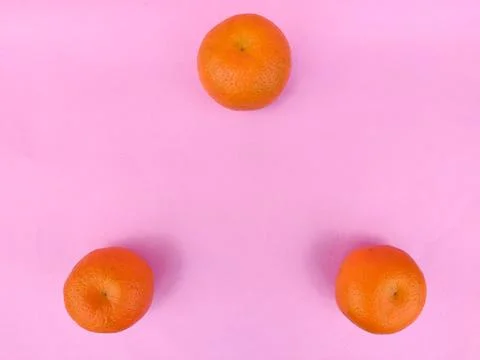 Three oranges in triangle shape.Isolated on pink background. Stock Photos