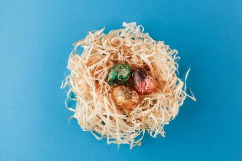 Three painted easter eggs lie in a nest of shavings. Stock Photos
