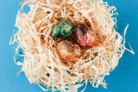 Three painted easter eggs lie in a nest of shavings. Stock Photos