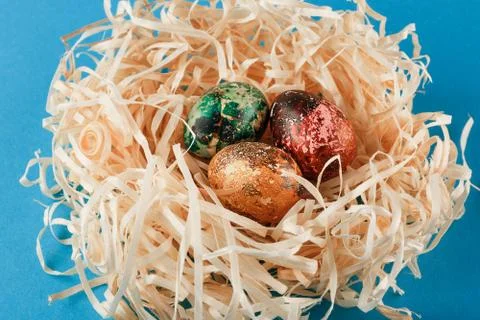 Three painted easter eggs lie in a nest of shavings. Stock Photos