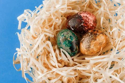 Three painted easter eggs lie in a nest of shavings. Stock-Fotos