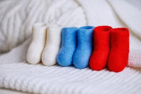 Three pairs of boots made of handmade wool in the colors of the Russian flag. Stock Photos