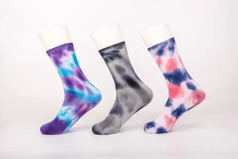 Three pairs of socks of different colors and styles are sleeved on the foot.. Stock Photos
