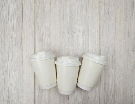 Three paper coffee cups placed on light wooden surface, eco-friendly packag.. Stock Photos