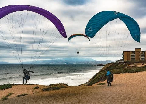 Three parafoils on the beach with dramatic cloudy skies and full surf Fotos de archivo