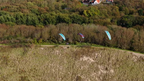 Three paragliders coastal speed soaring along Dutch dune 動画素材 325181791