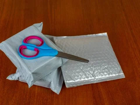 Three parcels and scissors lie on a dark table ready to be opened. Close up of Stock Photos