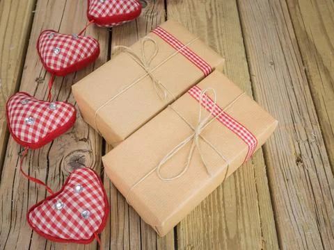 Three parcels wrapped with brown paper and string with red check ribbon aga.. Stock Photos