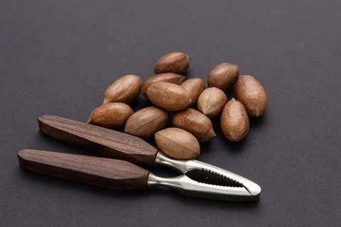 Three pecan nuts and nutcracker, isolated on white background. Stock Photos