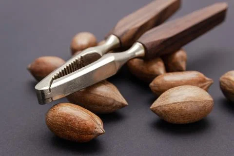 Three pecan nuts and nutcracker, isolated on white background. Stock Photos